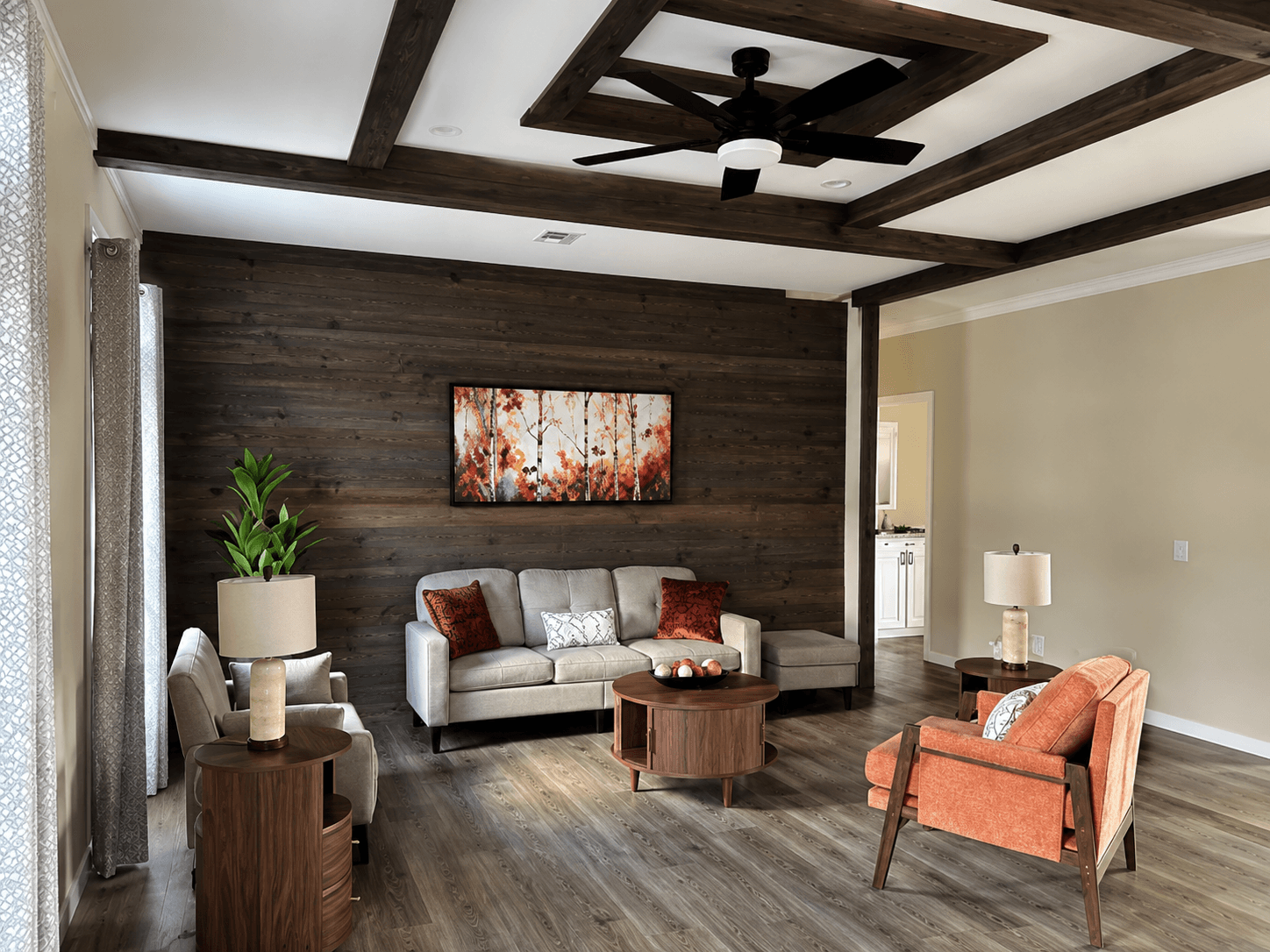 Furnished living room with a wood accent wall, grey sofa, terracotta chair and a forest painting